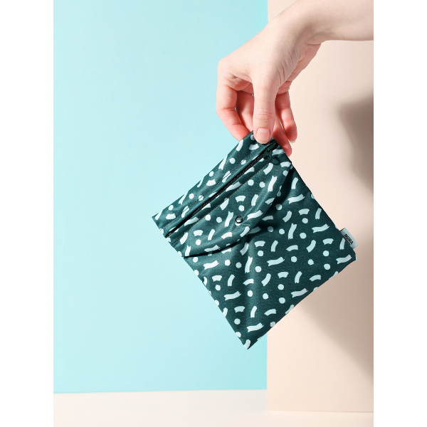 Period pad bag for out and about in Celeste Wiggle design (teal background with black splashes), held in a hand