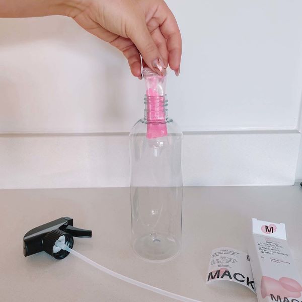 Mack reusable bottle with a hand placing a pod inside
