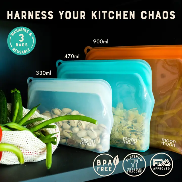 Moonmoon reusable silicone food bags, showing three sizes of bags side by side (small white, medium aqua and orange large) with different food inside, alongside a mesh cotton grocery bag with green beans. Text reads "Harness your kitchen chaos, washable reusable 3 bags, BPA free, platinum food grade silicone, FDA approved)