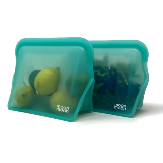 Reusable silicone food bags in xl size, with stand up functionality shown side by side with lemons and veg inside