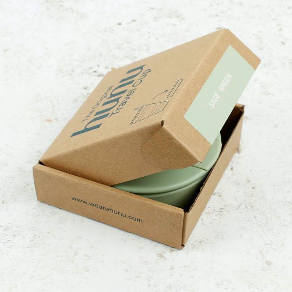 Collapsible cup shown in cardboard packaging with the lid up showing sage green cup inside