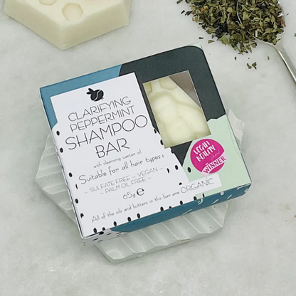 Clarifying peppermint shampoo barshown in simple cardboard packaging on a soap dish