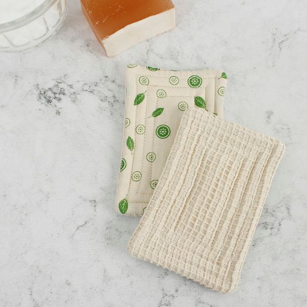 Pack of two mint kitchen unsponges, shown one with smooth side with mint leaf pattern and one with the natural coloured scrubby side, on a marble worktop