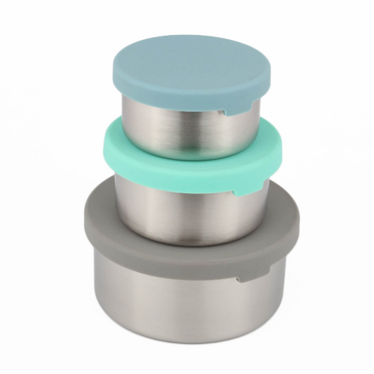 Stack of three metal food storage tubs with silicone lids in blue, green, and grey stacked one on top of each other on a white background