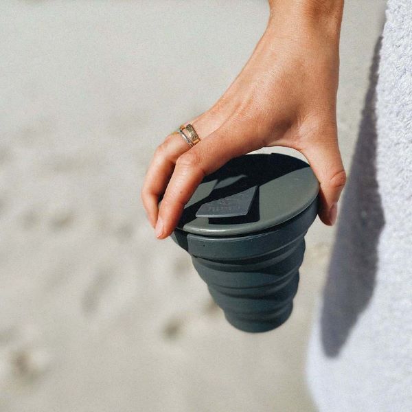 Collapsible cup shown in charcoal in a hand