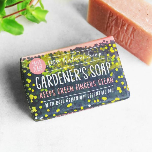 Gardener's soap bar shown wrapped and unwrapped with label saying "100% natural soap, keeps green fingers clean with rose geranium essential oil"