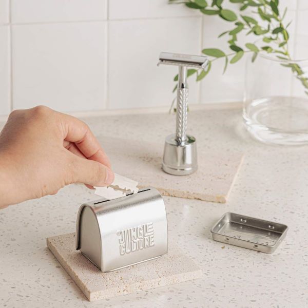 Hand popping a safety razor blade in the storage tin