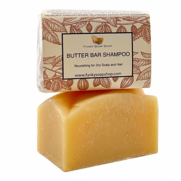 Funky Soap butter bar shampoo shown unwrapped and wrapped stacked on top of each other. Paper label reads "Butter bar shampoo, Nourishing for dry scalp and hair"