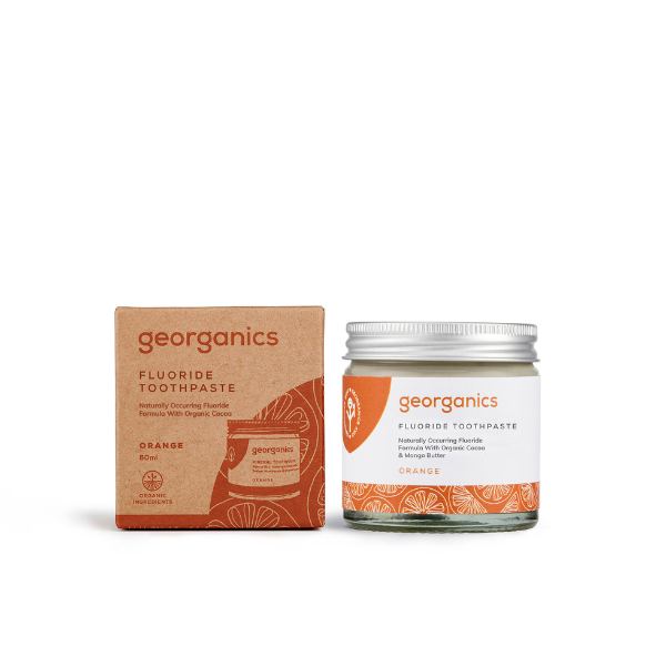 Georganics fluoride toothpaste with orange in glass jar alongside cardboard box