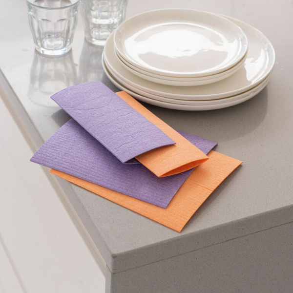 Compostable cloths rainbow bright (2 orange and 2 purple next to some dishes)