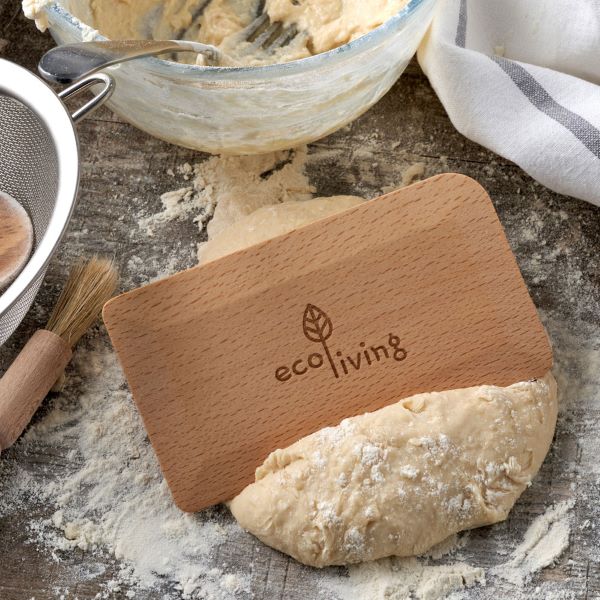 Wooden window or pastry scraper in use scraping some dough